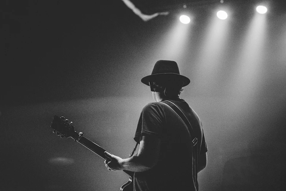 Man in black t-shirt and hat playing guitar
