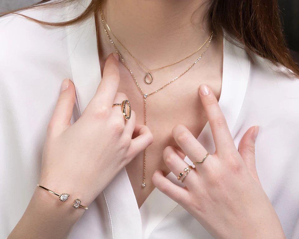 A close up of a person wearing rings and a necklace