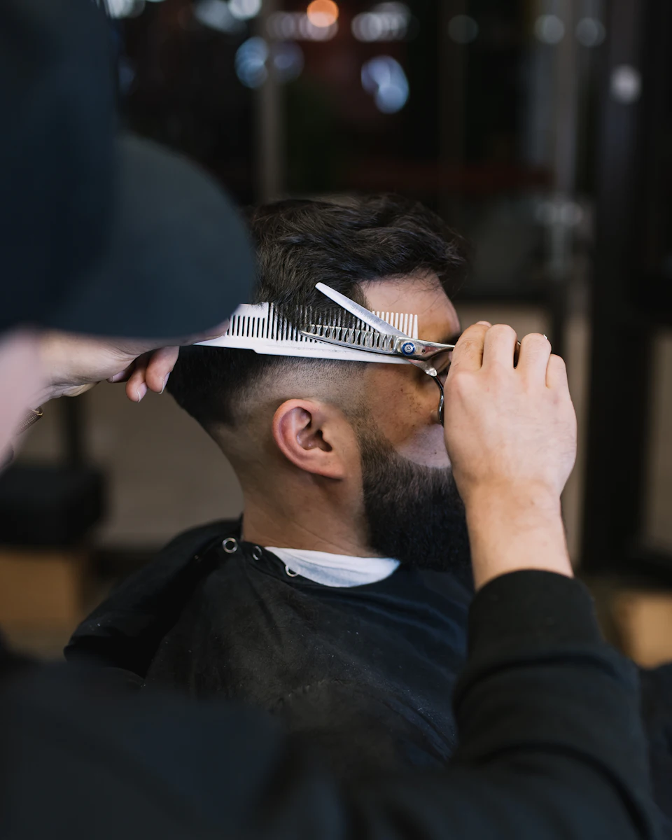 A man cutting another mans hair with a pair of scissors