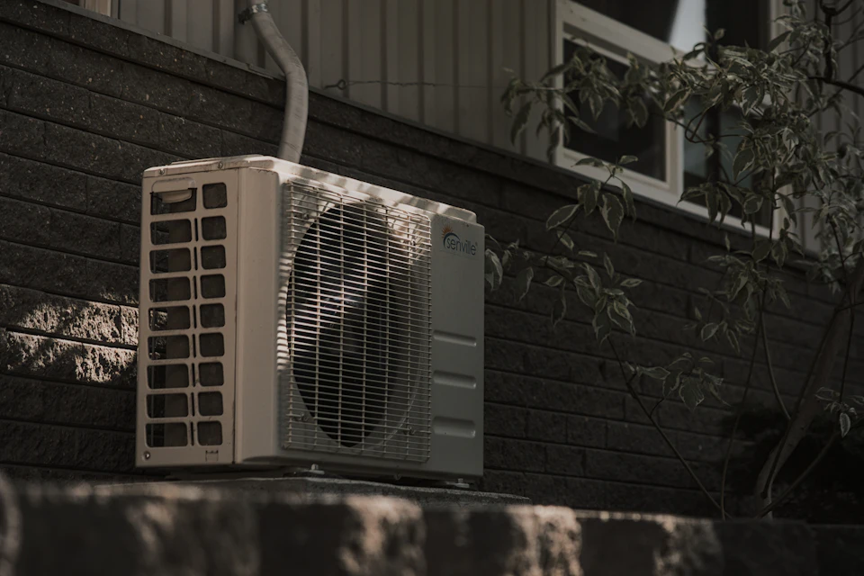 A white air conditioner sitting on top of a brick wall